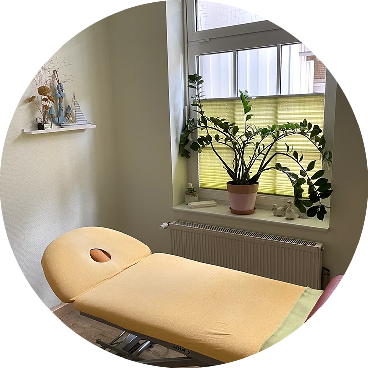 Heller Praxisraum mit gelber Liege und Fenster